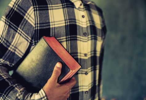 Jovem segurando bíblia nas mãos